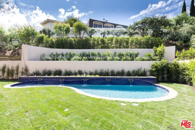 A look at this home's custom made swimming pool set on the wide lawn area of the property's backyard.