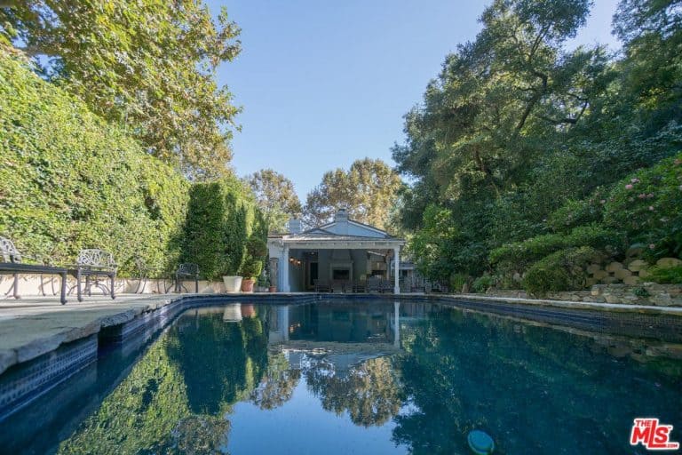 A close up look at this home's large swimming pool surrounded by tall and mature trees.