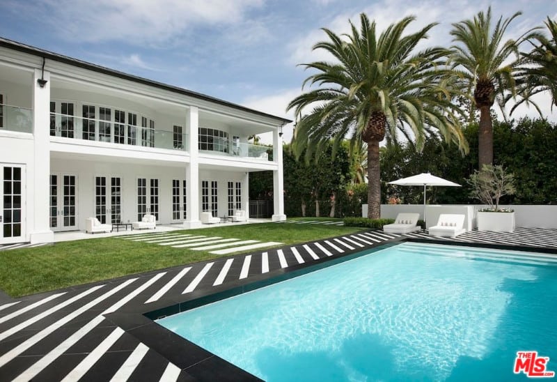 This house offers a stylish swimming pool area with a well-maintained lawn area on the side and has a walkway leading straight to the swimming pool.