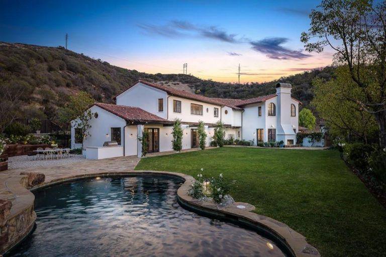 A large outdoor area featuring a wide lawn area and a gorgeous swimming pool. There's also an outdoor dining table set.