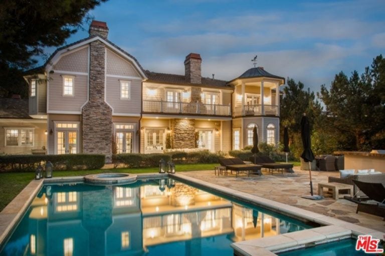 This large house offers a gorgeous outdoor area featuring well-maintained lawns and a swimming pool with sitting lounges on the side.