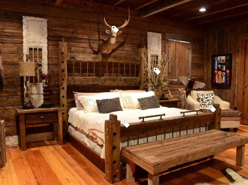A focused shot at this primary bedroom's rustic walls and a ceiling, along with hardwood flooring. The room offers a large bed set with rustic bedside tables.