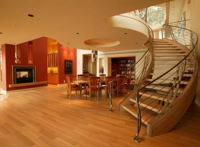 A spacious area of the home featuring a custom ceiling and hardwood floors, together with a glamorous curved chandelier with hardwood steps.