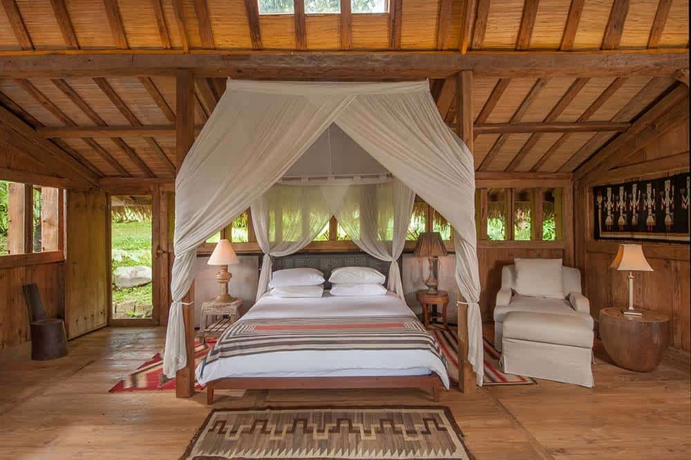 This is a full view of the bedroom with a shed wooden beam ceiling with skylight over the four-poster bed with curtains.