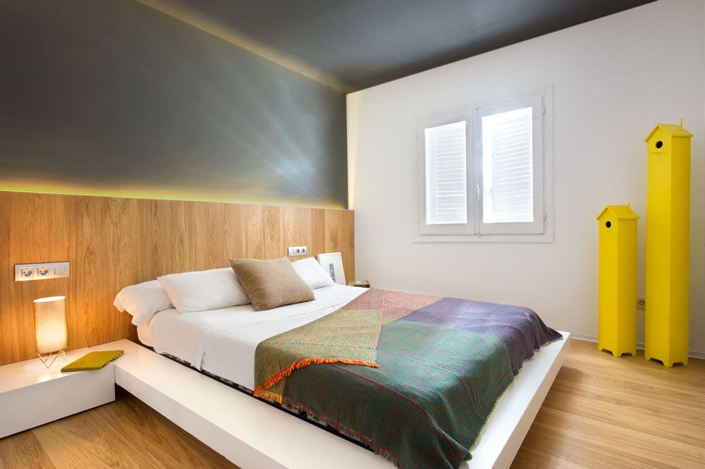 This primary bedroom boasts custom walls and ceiling, along with a modern bed setup with an attractive table lamp on the side.