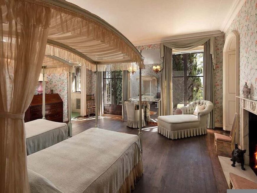 This primary bedroom offers a twin single bed and a fireplace on the side, along with a sitting area near the doorway. The room is surrounded by elegantly decorated walls.