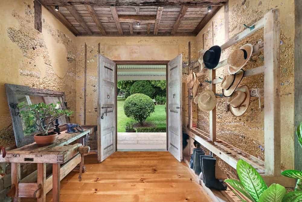 A mudroom entry foyer with rustic side table, a wooden shoe rack and a hat hanger.