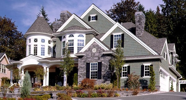 The lovely gray exterior walls of the house is complemented by the white accents and the colorful landscape of the front yard that has shrubs and medium-sized trees.