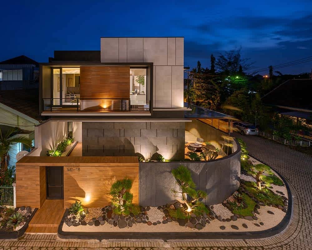 This is an aerial view of the house exterior showcasing the landscaping that has a Zen garden lining the outer walls of the house with outdoor lighting that matches the windows of the house.