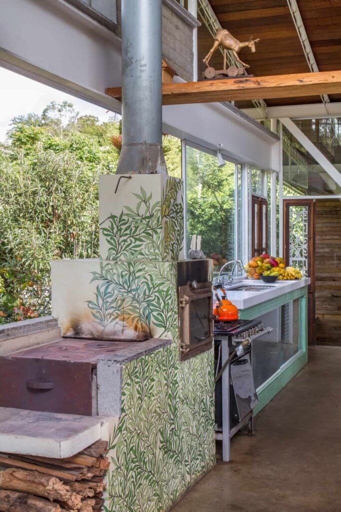 A rustic kitchen featuring a classic oven set and a single wall kitchen counter with a white countertop. The area is set under the home's high rustic ceiling.