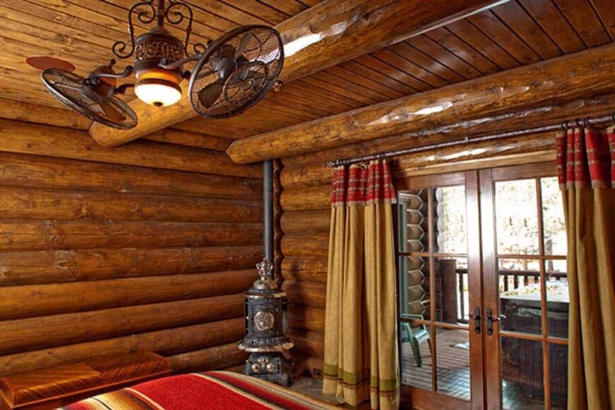 The primary bedroom with a fireplace, vintage ceiling fan, and French doors leading to the porch.