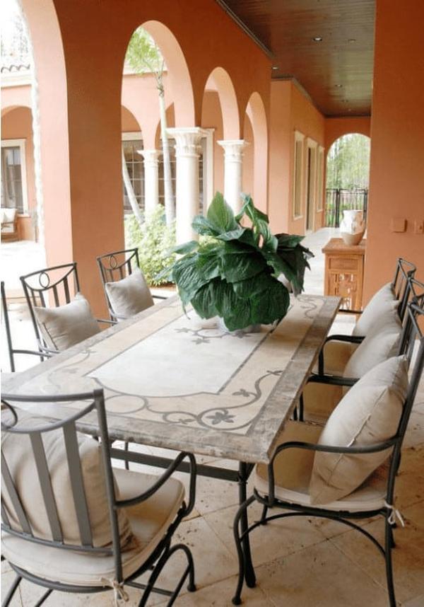 Charming outdoor dining area with arched walls, cushioned chairs, and a decorative stone table.