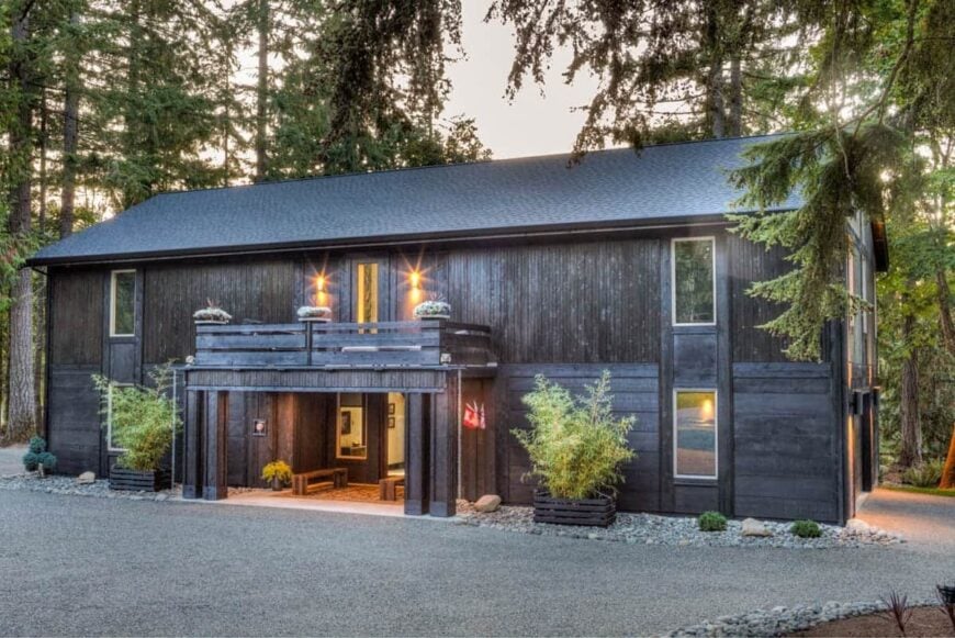Home's facade with a gable roof, rustic wood cladding and an entry porch under the sun deck.