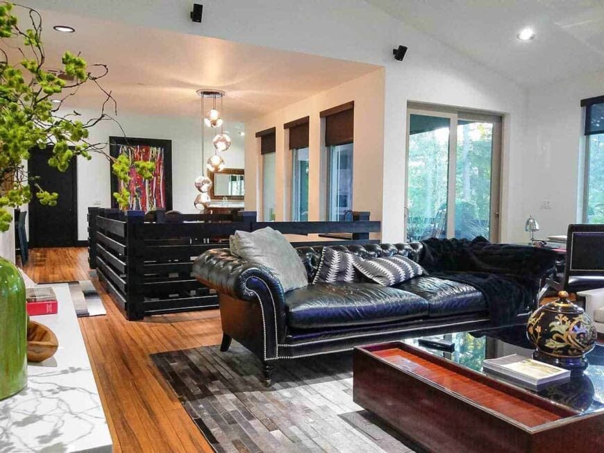 Living room with a black chesterfield sofa and a large coffee table over the textured area rug.