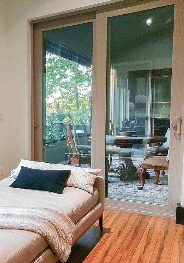 Junior suite with glass sliding doors and a single bed over wide plank flooring.