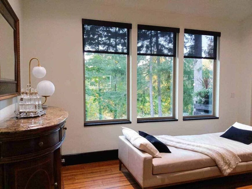 Across the single bed is a semi-circular console table paired with a wooden framed mirror.