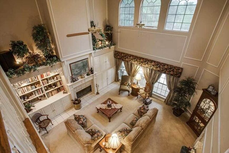 The top view of the family room shows the towering ceiling and white framed windows dressed in floral valance and sage drapes.