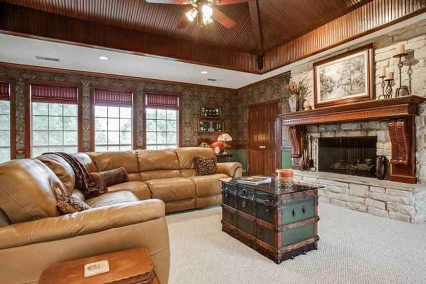 Living room with a stone fireplace and a brown leather sectional paired with a chest trunk coffee table.