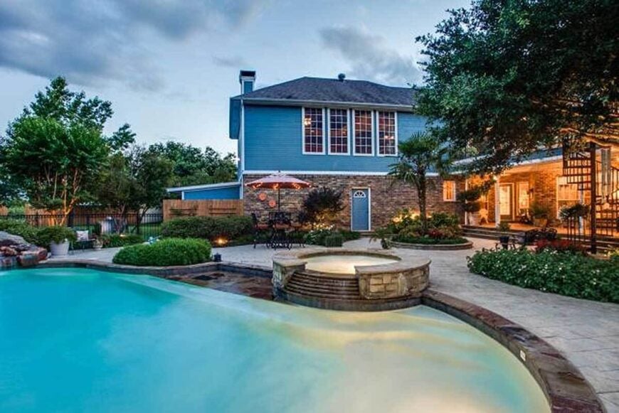 Home's rear view shows the covered patio and the courtyard filled with a sparkling pool and an integrated spa.