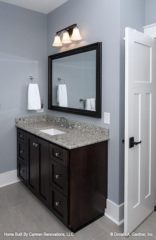 There's also a sink vanity with a granite countertop paired with a framed mirror and glass sconces.