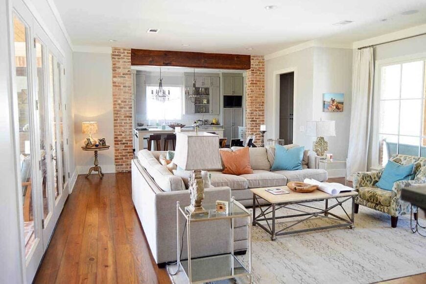 The living room has a metal coffee table, a printed armchair and a gray L-shaped sectional accented with pastel pillows.
