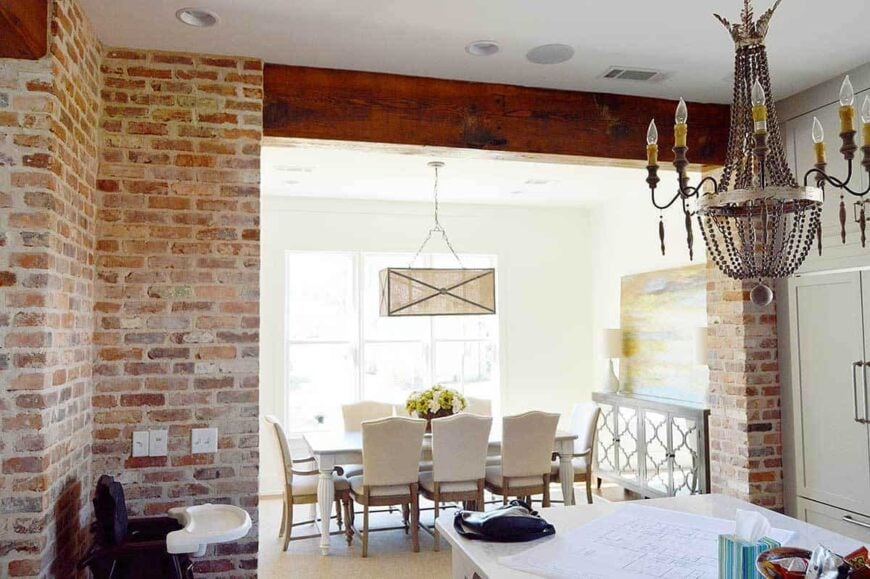 The dining room offers a rectangular pendant light, white dining set, and a classy mirrored buffet topped with a sleek table lamp and abstract painting.