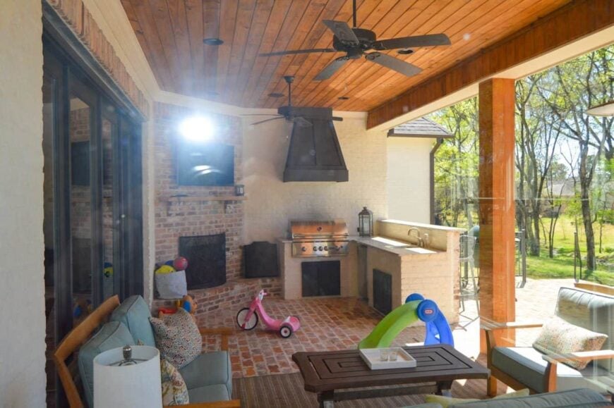 The rear covered porch is filled with outdoor living, a summer kitchen, and a corner fireplace with a TV on top.