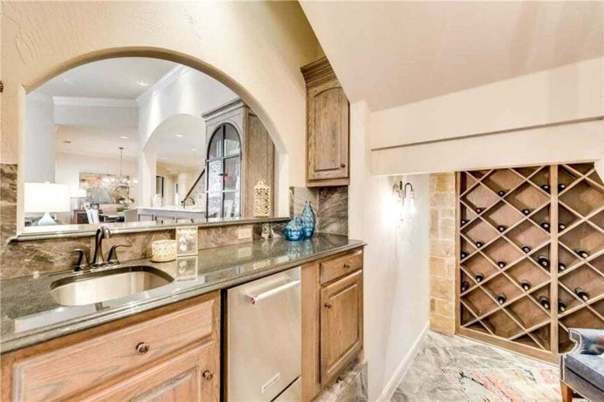 Bar with wooden cabinets, undermount sink, and an arched window overlooking the family room.