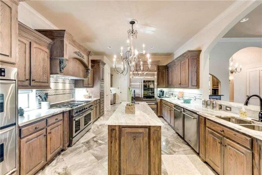 The galley kitchen is equipped with stainless steel appliances, a marble top island, and dual sink paired with a gooseneck faucet.