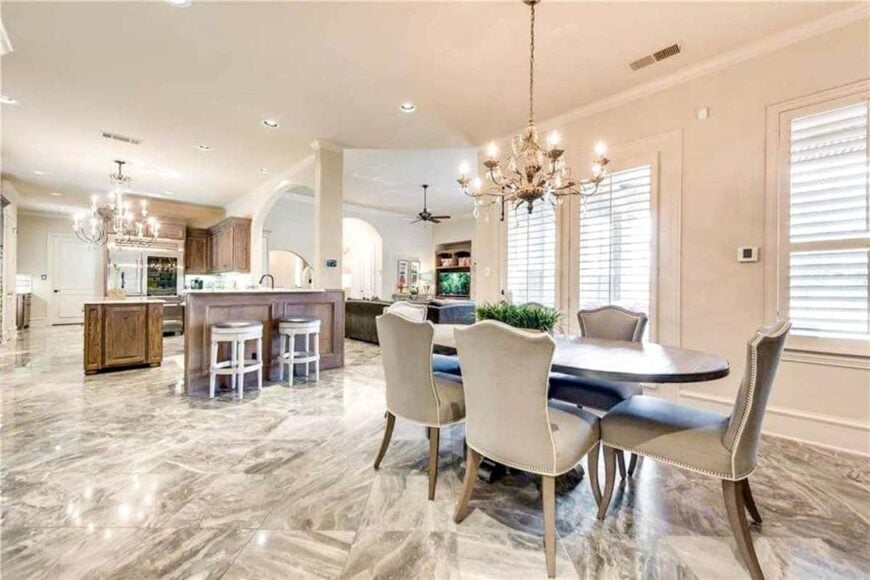 The breakfast nook offers gray upholstered chairs and an oval dining table illuminated by a warm chandelier.