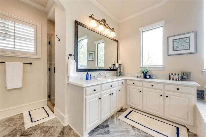 The opposite side view shows another vanity and the walk-in shower complemented with bordered rugs.