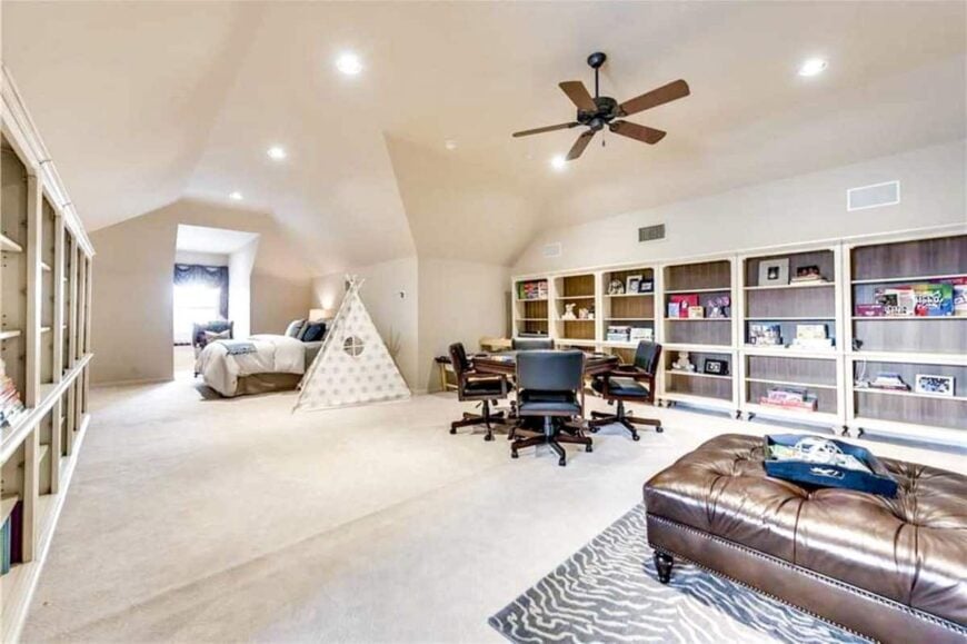 The bonus room has beige carpet flooring, vaulted ceiling, cozy seats, a bed, and lots of built-in shelves.