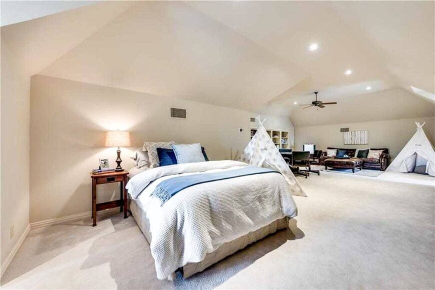 A closer look at the comfy bed accompanied by a teepee tent and a wooden nightstand topped with a drum table lamp.