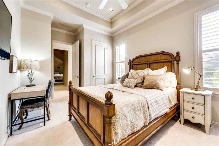 This bedroom has a lighter color scheme complemented with a wooden bed and a light wood desk that matches the nightstands.