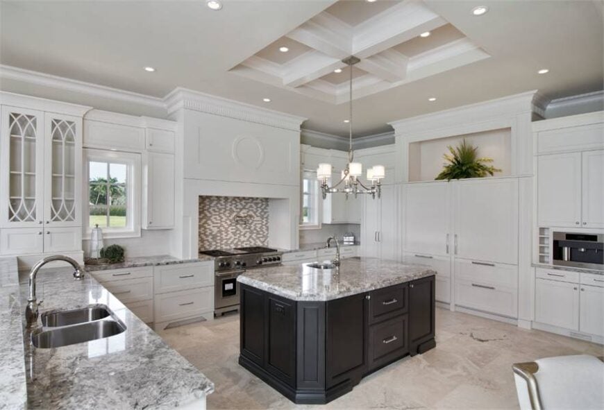 A closer look at the kitchen shows the granite top central island surrounded by pristine white cabinetry.