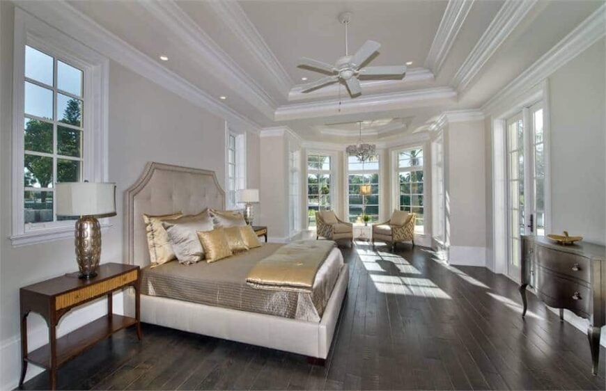 The primary bedroom features a tufted platform bed and a sitting area by the bay window.