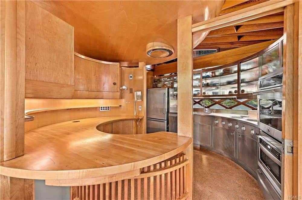 This is the charming kitchen dominated by the wooden elements of the ceiling, hardwood flooring and the built-in wooden curved counted with a wooden column.