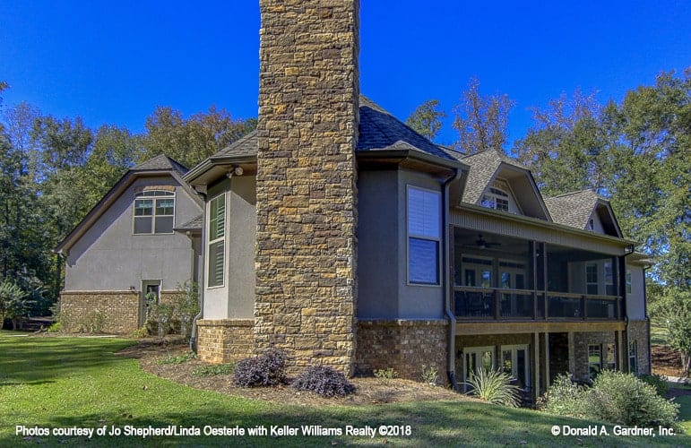 The home's angled view shows the rear porches and a brick chimney attached to the side.