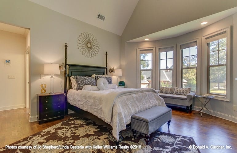 Primary bedroom with a soaring cathedral ceiling and a sitting area by the bay window.