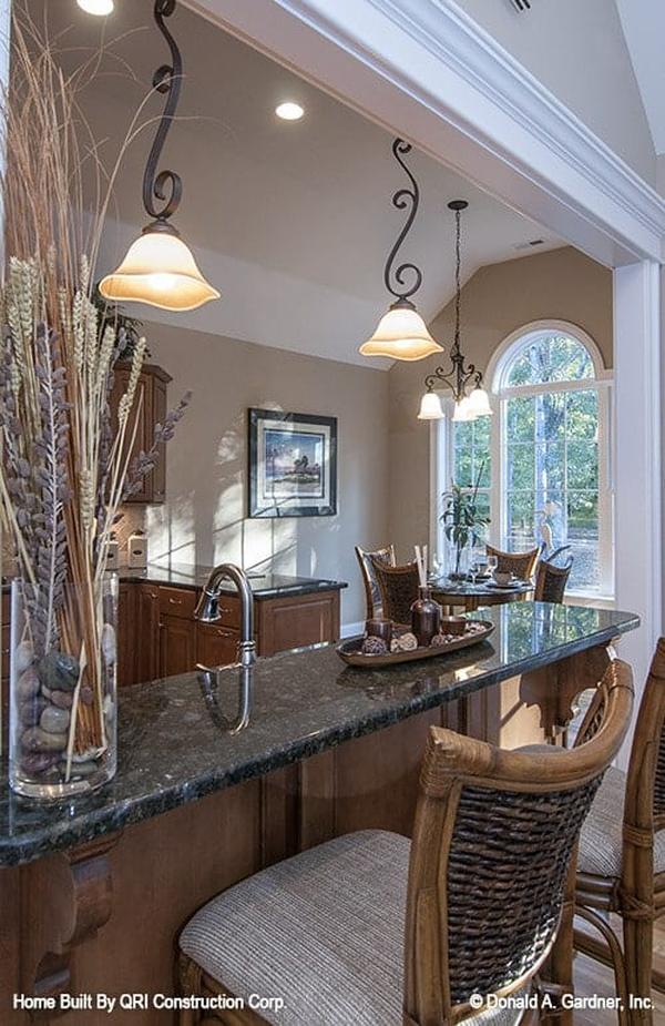 The black granite top peninsula is complemented with wicker counter chairs and ornate pendant lights.