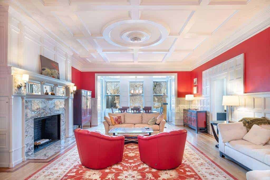 This spacious living room features a white walls with a touch of red that matches the red sofa on the red gorgeous rug.