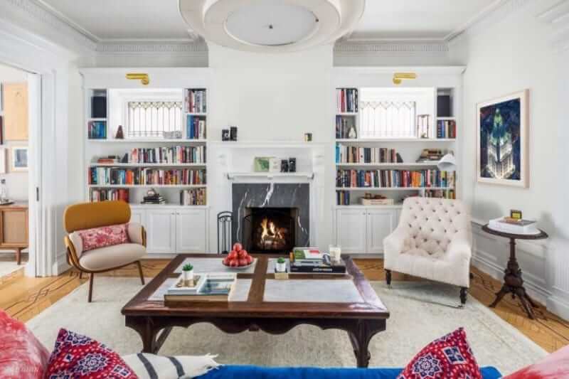 The spacious living room features a large wooden table on the stylish carpet and a fireplace that warms the area.