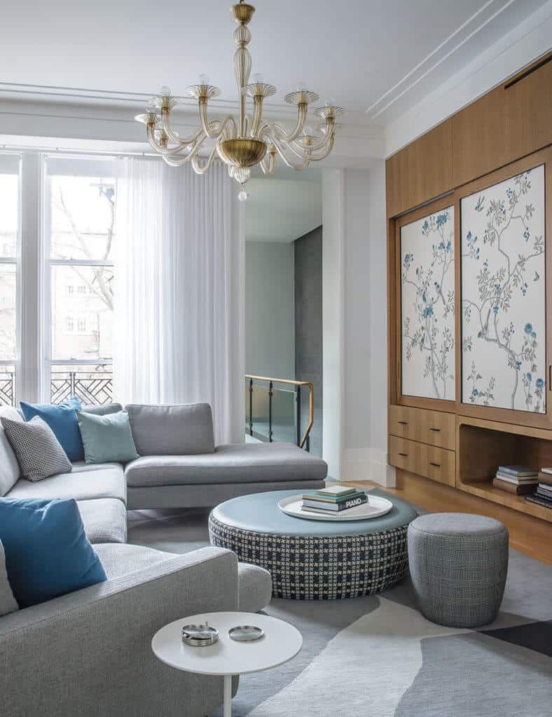 There is a large area rug which matches the furniture. Designs on the ottoman and the wall panels, along with the colors of the accent pillows help to add life to space.
