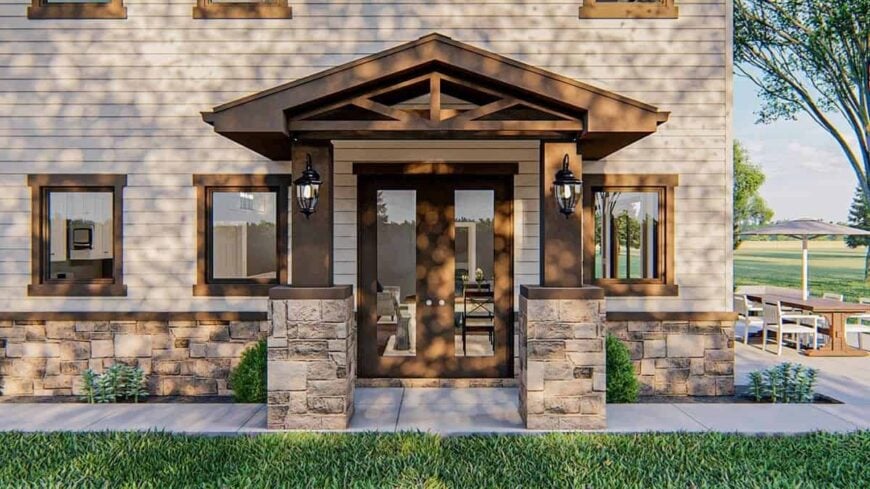 The front porch with a french door is enclosed in stone columns and a decorative gable roof.