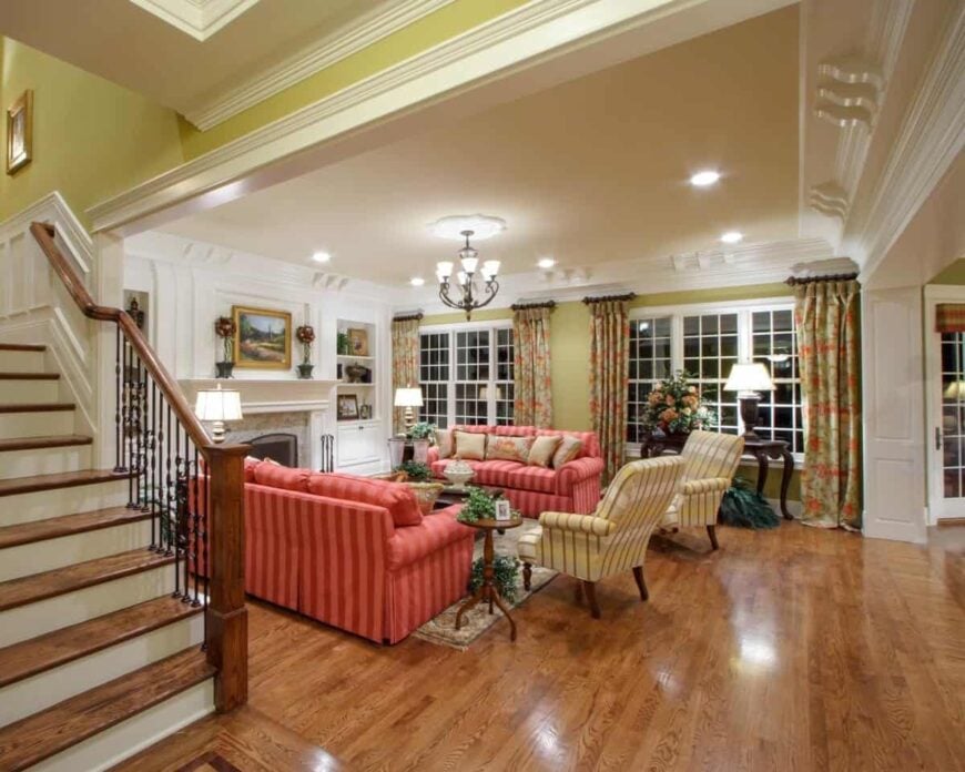 The living room offers red striped sectionals and yellow armchairs facing the marble fireplace.