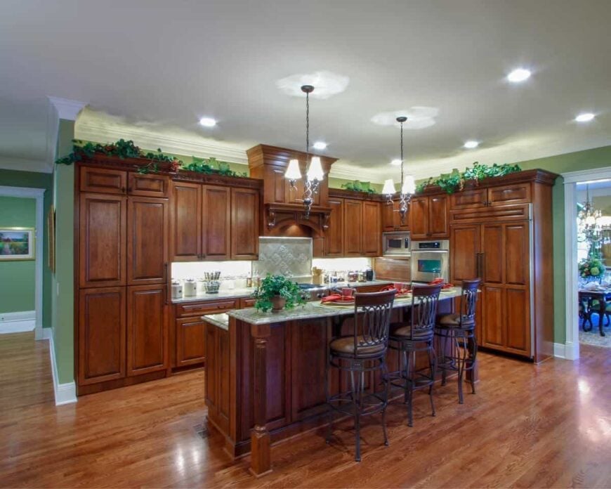 An angled view shows the two-tier breakfast bar that blends in with the wooden cabinetry and hardwood flooring.