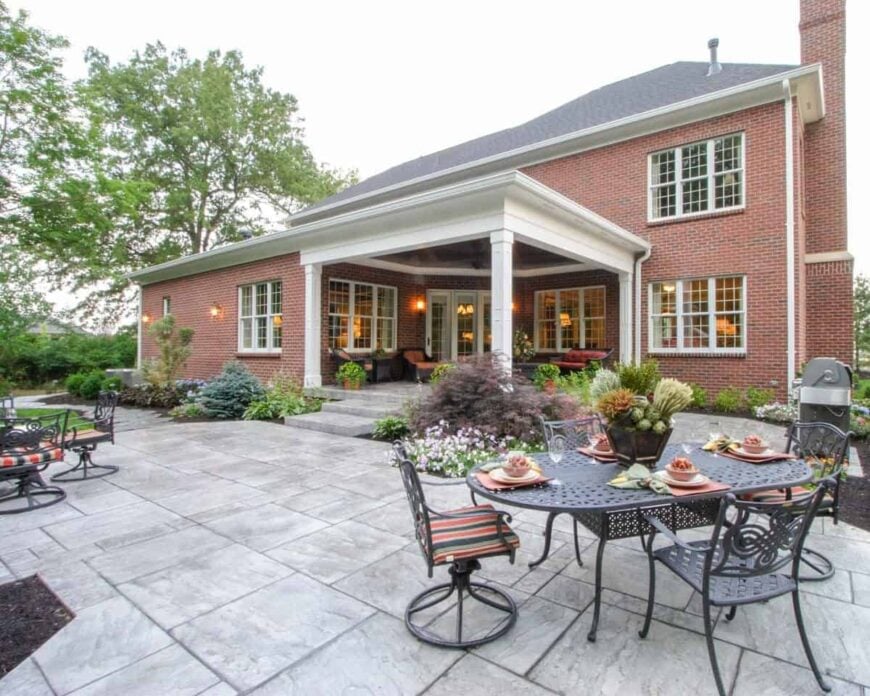 The open patio has concrete tiled flooring, multiple metal seats, and an outdoor grill station.