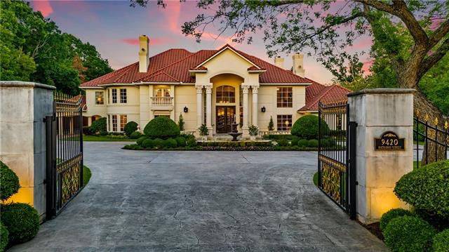 The wrought iron main gate opens to this mansion with clay tile roofing, exterior siding, and greek columns supporting the front porch.