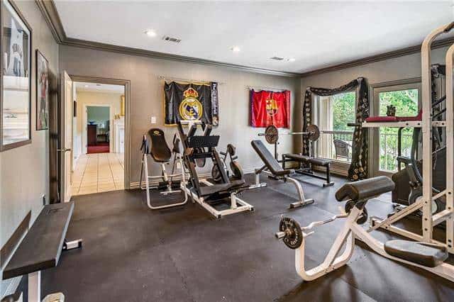 Exercise room with rubber flooring and gray walls adorned by posters and tapestries.