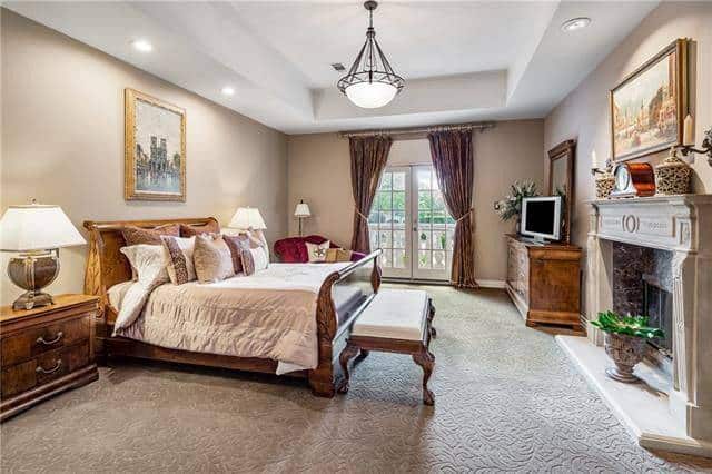 Bedroom with wooden furniture, a fireplace and french door that leads out to the balcony.